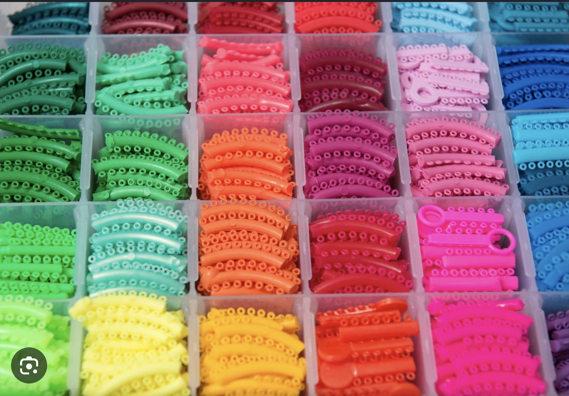 Tray of colorful orthodontic ligature ties in every shade — red, pink, blue, purple, and more