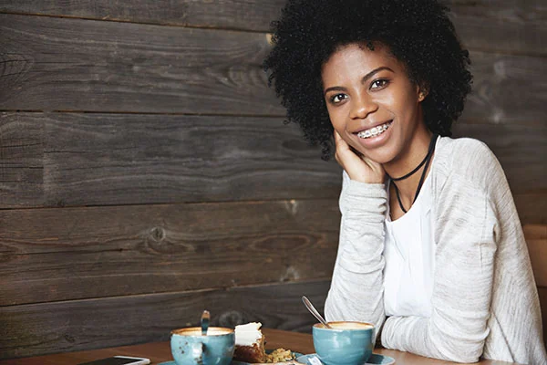 Adult patient smiling with braces at a cafe