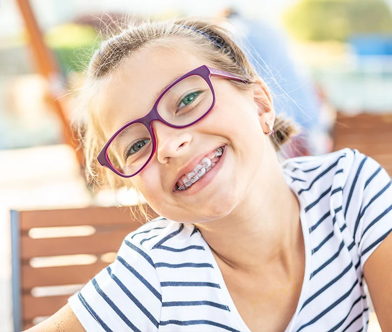 Young child with braces smiling outdoors
